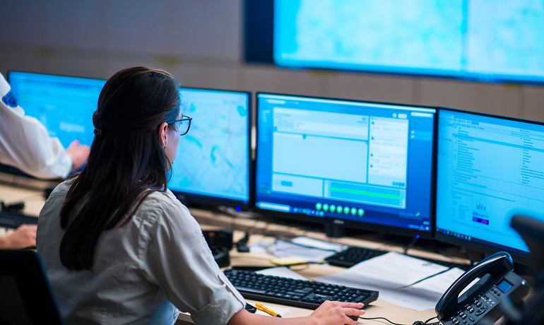 Donna lavora al computer monitorando i dati su diversi monitor contemporaneamente