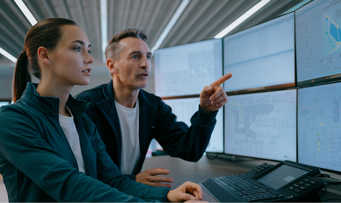 Un uomo e una donna lavorano al computer. L'uomo indica dei dati sullo schermo.