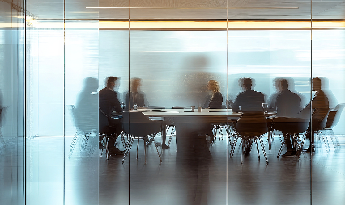 Uomini e donne in abiti formali sono seduti intorno a un tavolo, impegnati in una riunione di lavoro